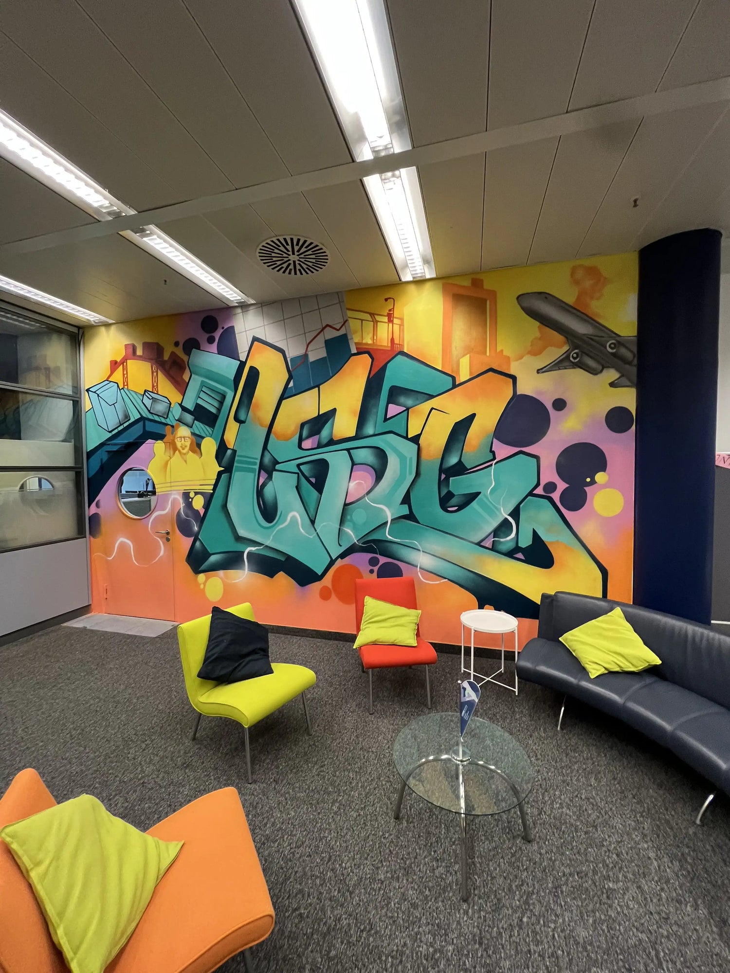 Bunte Graffiti-Wandgestaltung in einem Innenraum mit Lounge-Bereich, Sofas und moderner Street-Art-Wandmalerei