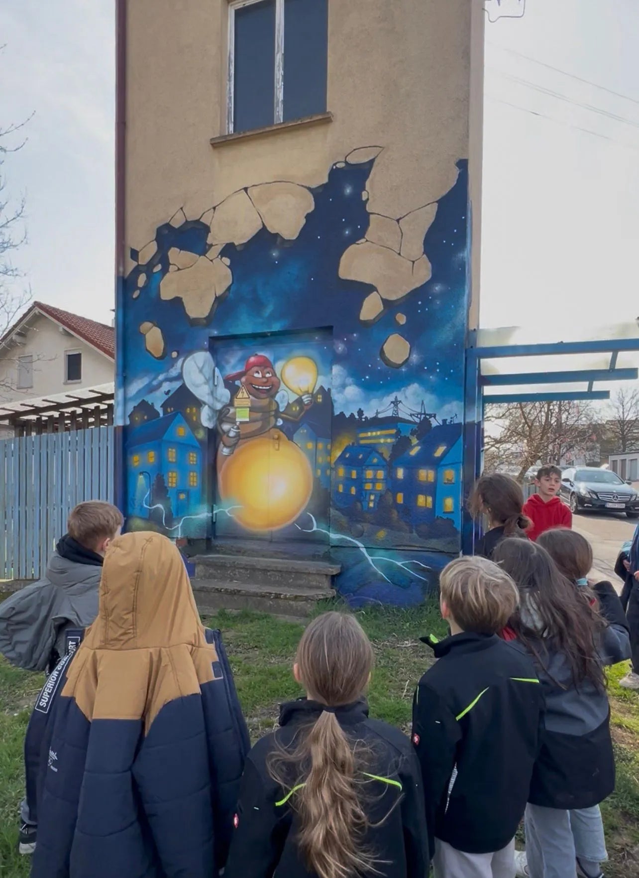 Kinder betrachten eine bunte Graffiti-Wandgestaltung bei einem Street-Art-Workshop im Außenbereich