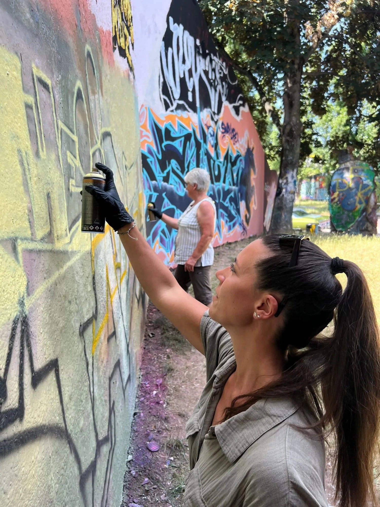 Teilnehmerin sprüht mit einer Spraydose bei einem Graffiti-Workshop an einer Street-Art-Wand